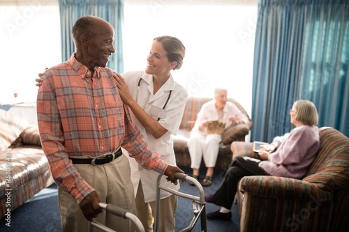 Smiling senior man with walker looking at female doctor against