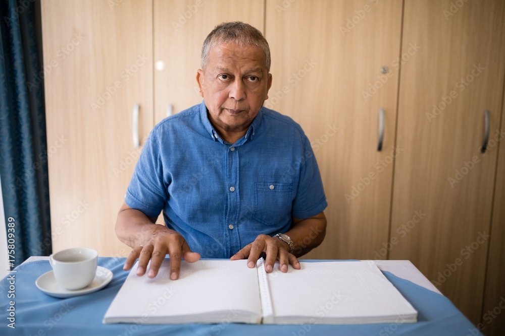 Senior man sitting with book and coffee cup at table Senior man sitting with book and coffee cup at table