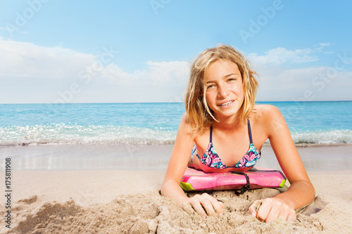 Blond girl with surfboard lay on sea beach