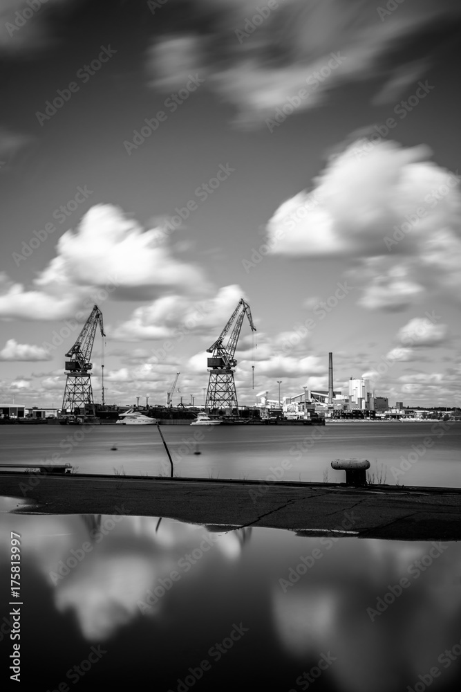 Harbor of Kotka large cranes are reflected in the sea under the cloudy sky