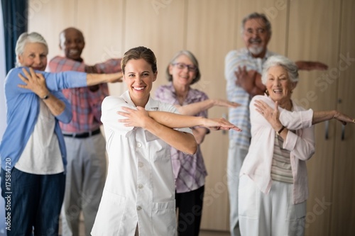 Portrait of smiling female doctor and seniors stretching arm