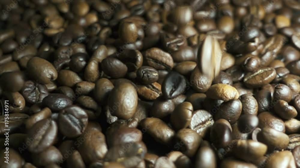 Roasted coffee beans with coffee dust falling down. Slow motion Roasted coffee beans with coffee dust falling down. Slow motion