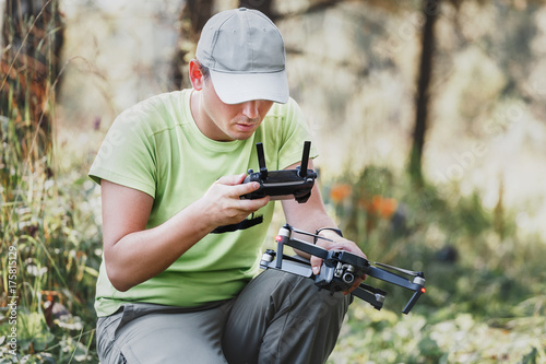 closeup on male hands of drone operator with an amateur quadcopter remote control joystick, outdoors