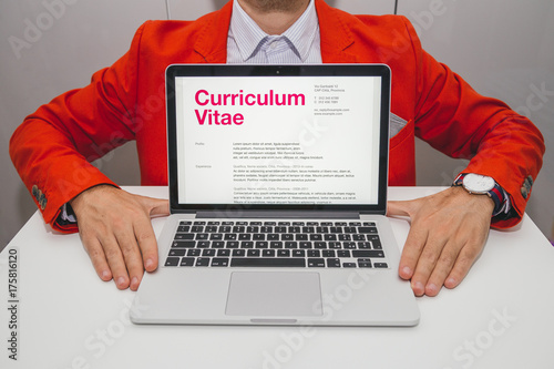 Man showing curriculum vitae on laptop. Foreign text is latin. Text meaning: generic CV pre filled. All data showing a generic format for cv, without reference to someone or somewhere.