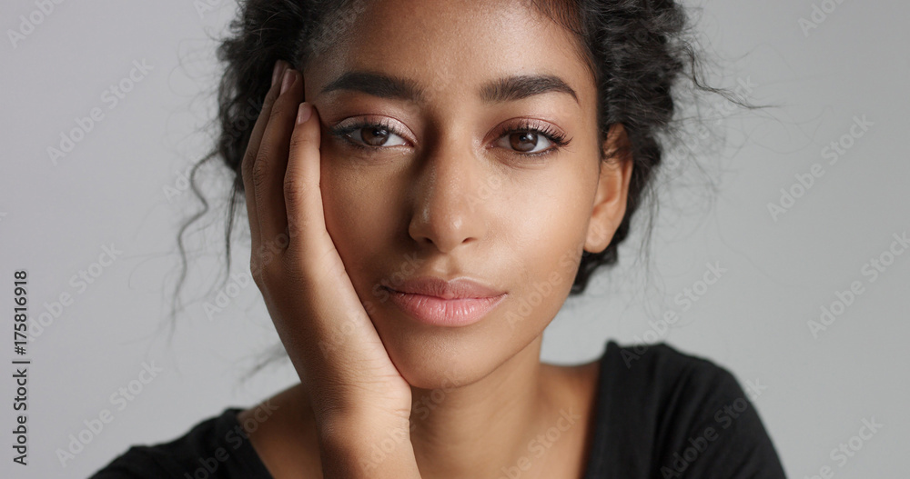 Attractive young Middle Eastern model touching her pretty face with flawless skin and smiling