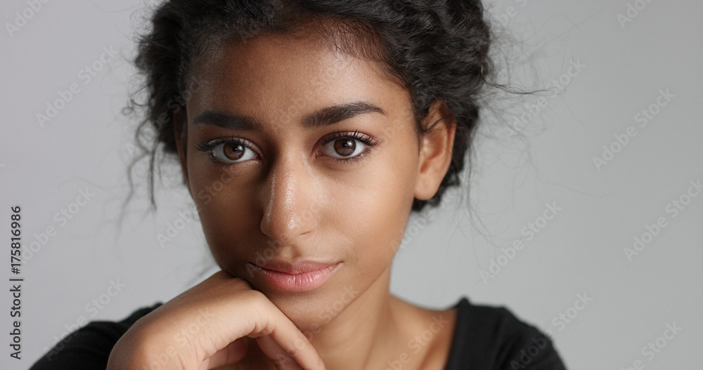 Fototapeta premium young girl with perfect light brown skin and beautiful curly black hair smiling at the camera in studio