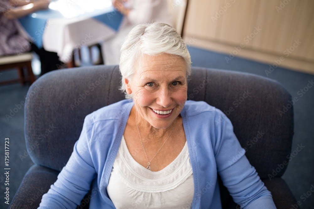 High angle view of smiling senior woman sitting on armchair High angle view of smiling senior woman sitting on armchair