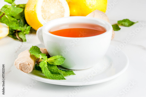 Cup of ginger tea with lemon,fresh mint and honey, on white marble table, copy space