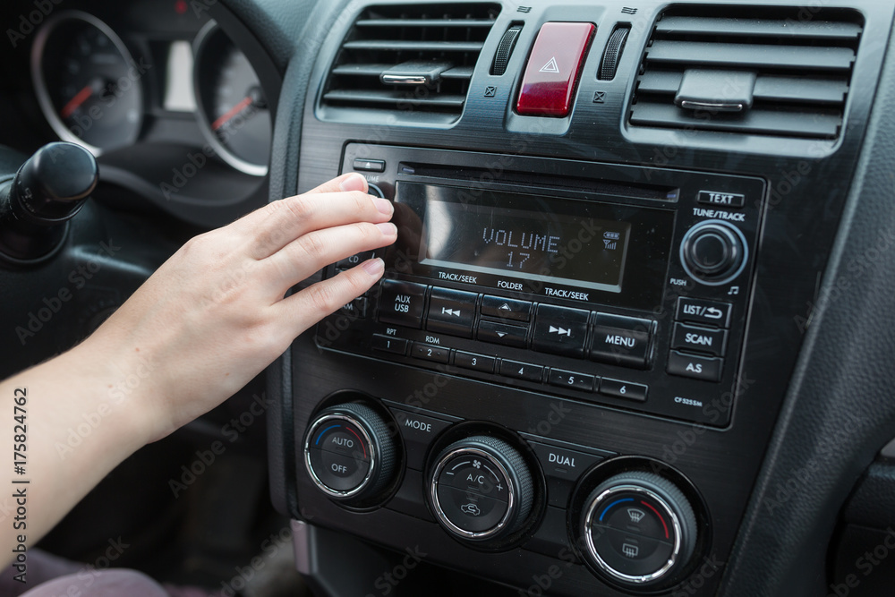 Fototapeta premium woman turning button of radio in car