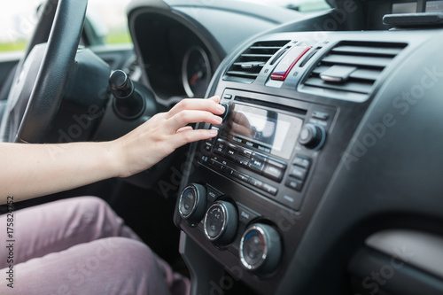 woman turning button of radio in car © 4frame group