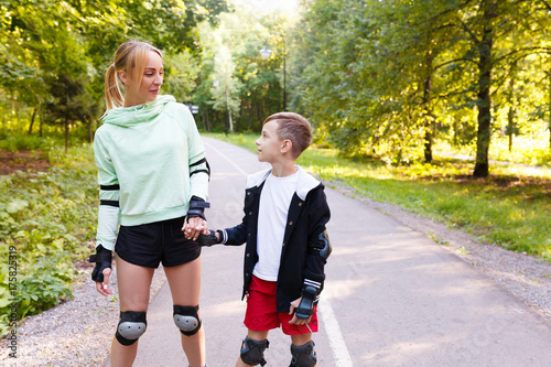 Happy young family roller skating in park photo