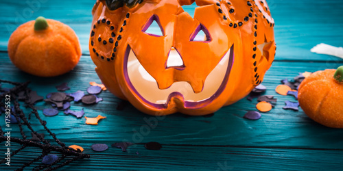 Halloween trick or treat still life on dark green. Toy pumpkin, sweets, marshmalllow, confetti. Holiday mood background banner