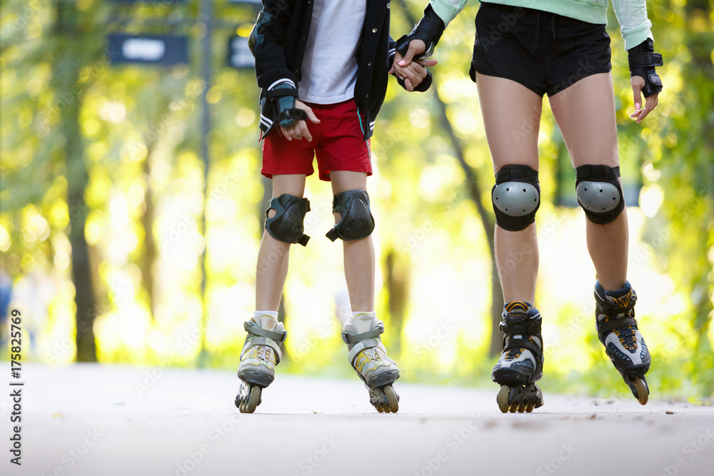 Happy young family roller skating in park