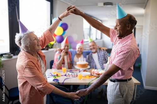 Senior couple making frame against friends at birthday party