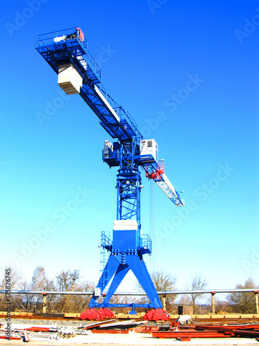 The crane stands on the rails against the blue sky.