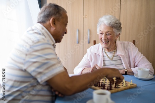 Smiling male and female seniors playing chess at table