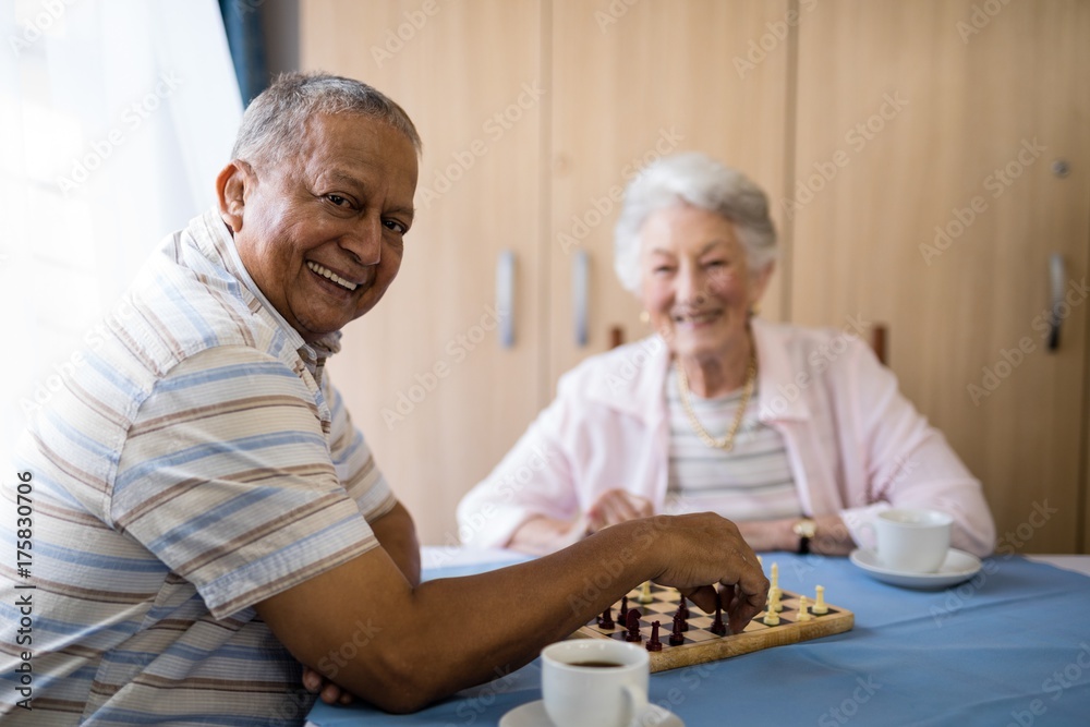 Smiling senior man playing chess with friend Smiling senior man playing chess with friend