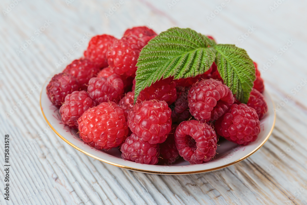 Raspberries in a bowl on a wooden white table Raspberries in a bowl on a wooden white table