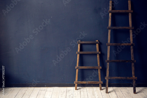 two wooden ladders stand at the blue wall on white floor