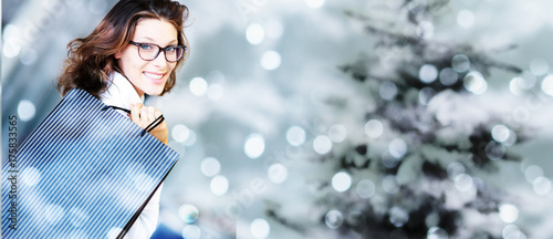 Fotografi christmas shopping, smiling woman with bags on blurred bright li