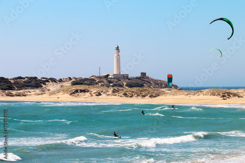People doing kitesurfing on the beach of Los Canos de Meca, next to the lighthouse of Trafalgar, on the coasts of Cadiz, Spain