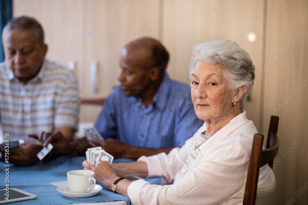 Portrait of senior woman sitting with friends while playing Portrait of senior woman sitting with friends while playing