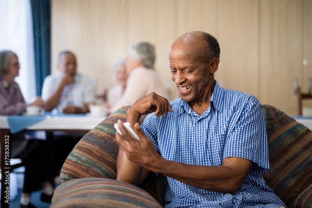 Fotografie Smiling senior man looking at mobile phone