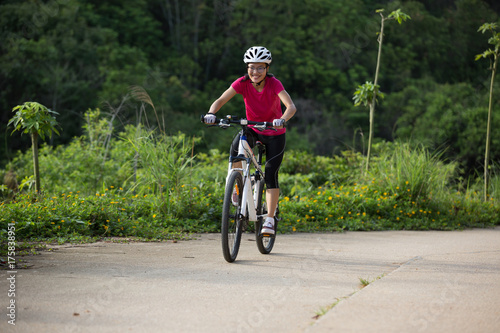 woman cyclist cycling on summer forest trail