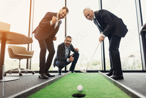 Foto A respectable elderly man is playing golf in his office