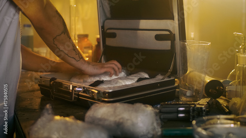 Valokuva In the Underground Laboratory Hardcore Dealer Places Brick Packs Filled with Drugs Into the Suitcase for Further Selling and Distribution