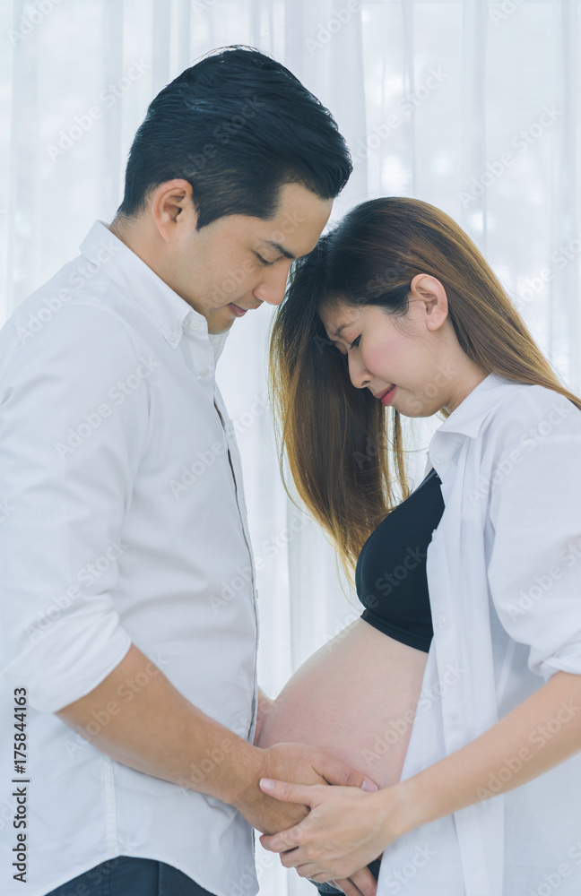 Beautiful pregnant woman and her handsome husband are touching care tummy Beautiful pregnant woman and her handsome husband are touching care tummy