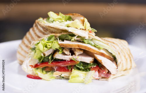 Burrito with grilled chicken and vegetables. Shawarma from juicy beef, lettuce, tomatoes, cucumbers, paprika and onion in pita bread.