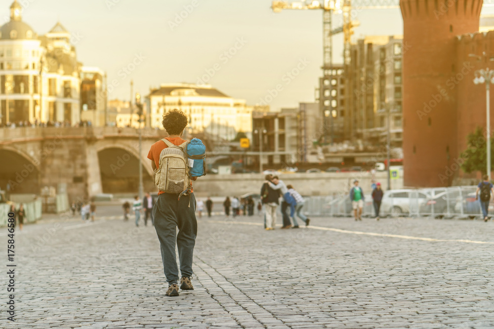 traveler with backpack walking in the city Moscow and sunlight with sunset background