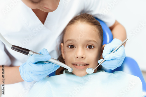 A little girl at a reception with a dentist. Female doctor preparing to examine the teeth of a girl