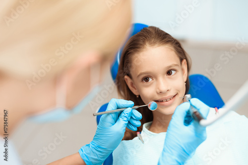 A little girl at a reception with a dentist. Female doctor preparing to examine the teeth of a girl. Girl smiling