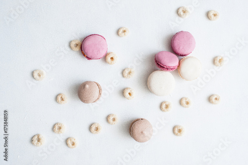 Background of colourful sweets top view. Colorful delicious macaroons and breakfast cereal on white backdrop