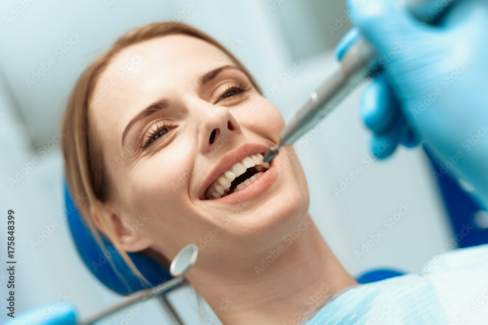 A woman is sitting in a dental chair, doctors dentists bent over her A woman is sitting in a dental chair, doctors dentists bent over her