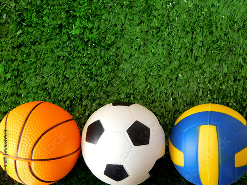 Balls for soccer  basketball and volleyball are lying on the green grass. Different sports concept