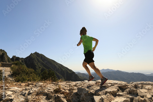 young fitness woman trail runner running on top of mountain