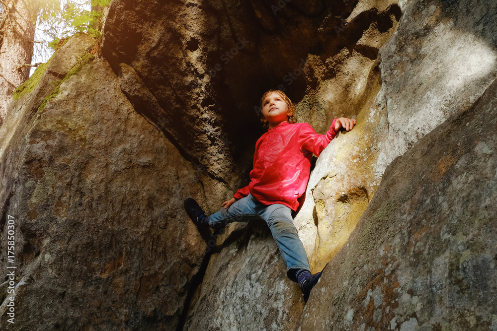 Small boy climbing on the rocks in the forest Small boy climbing on the rocks in the forest