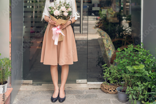 Cropped image of woman standing in flower shop and holding bouquet of flowers