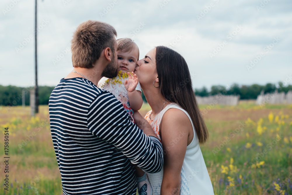 young happy family with little beautiful baby with blue eyes walking in summer park at sunset. young happy family with little beautiful baby with blue eyes walking in summer park at sunset.