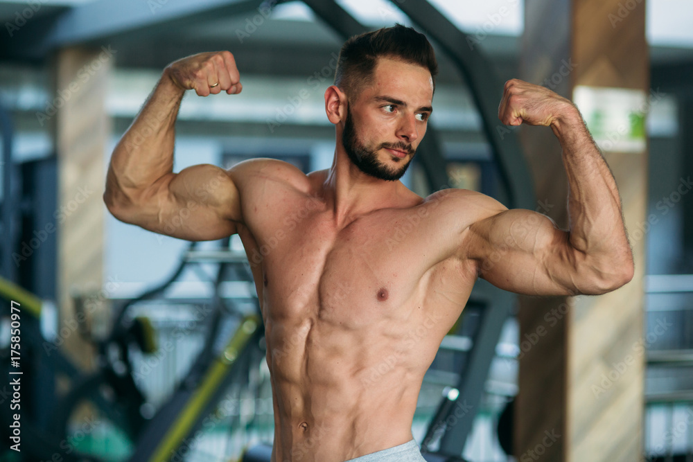 Young athlete posing with a torso for photography on a brick wall background. Bodybuilder, athlete with pumped muscles. Young athlete posing with a torso for photography on a brick wall background. Bodybuilder, athlete with pumped muscles.