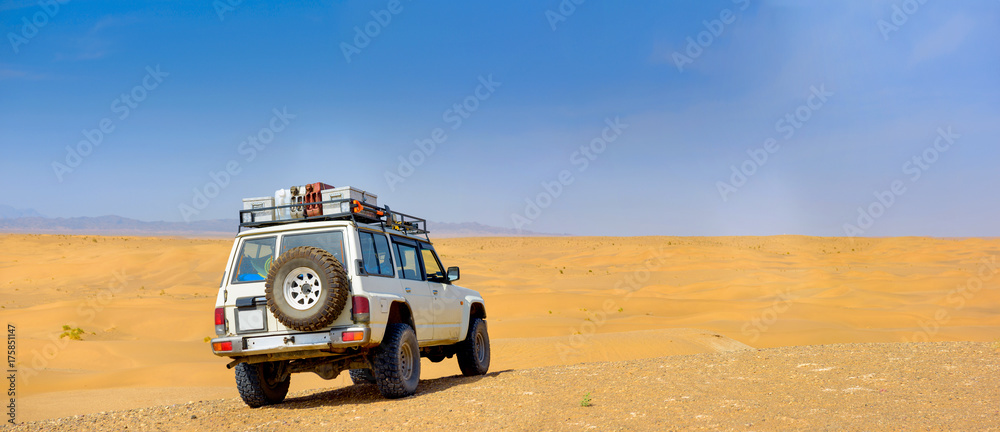 View of the sandy desert from the high dune on which the SUV stands, travels