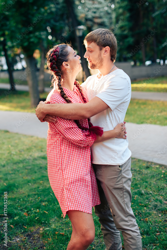 young loving couple in the park outdoors against the trees young loving couple in the park outdoors against the trees