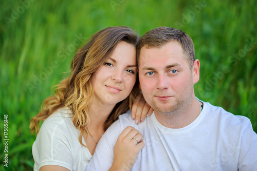 happy young couple walking in beautiful park, sitting on grass and hugging