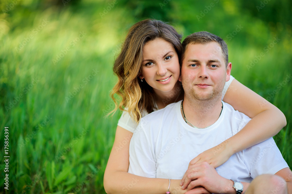 happy young couple walking in beautiful park, sitting on grass and hugging happy young couple walking in beautiful park, sitting on grass and hugging