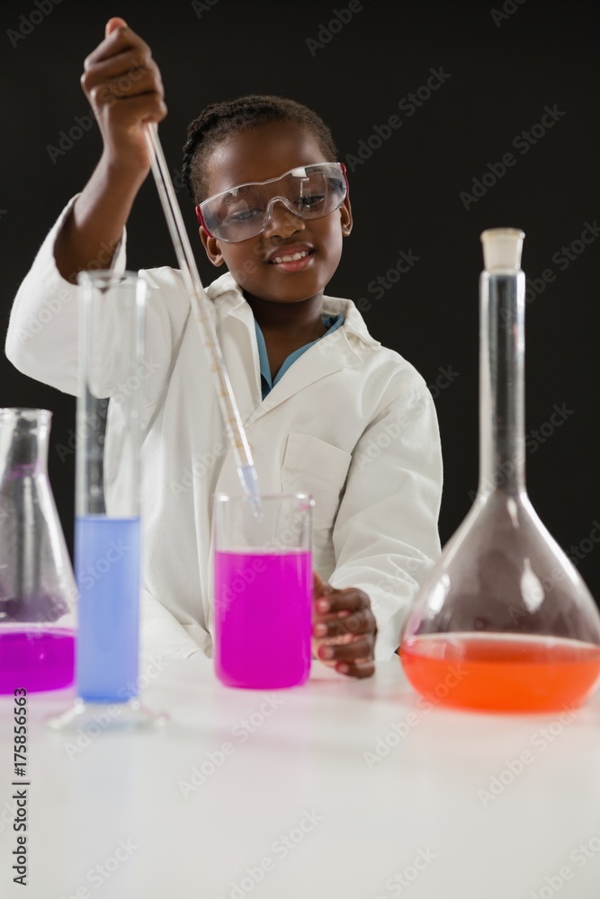 Schoolgirl doing a chemical experiment against black background Schoolgirl doing a chemical experiment against black background