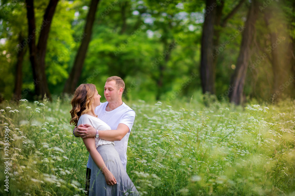 happy young couple walking in the evening park, gently hugging and smiling