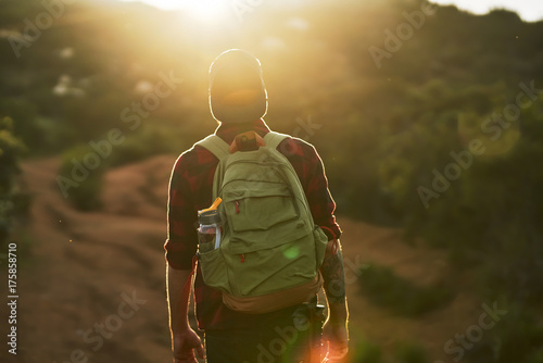 male millennial hiker trekking up trail in southern california during sunset photo